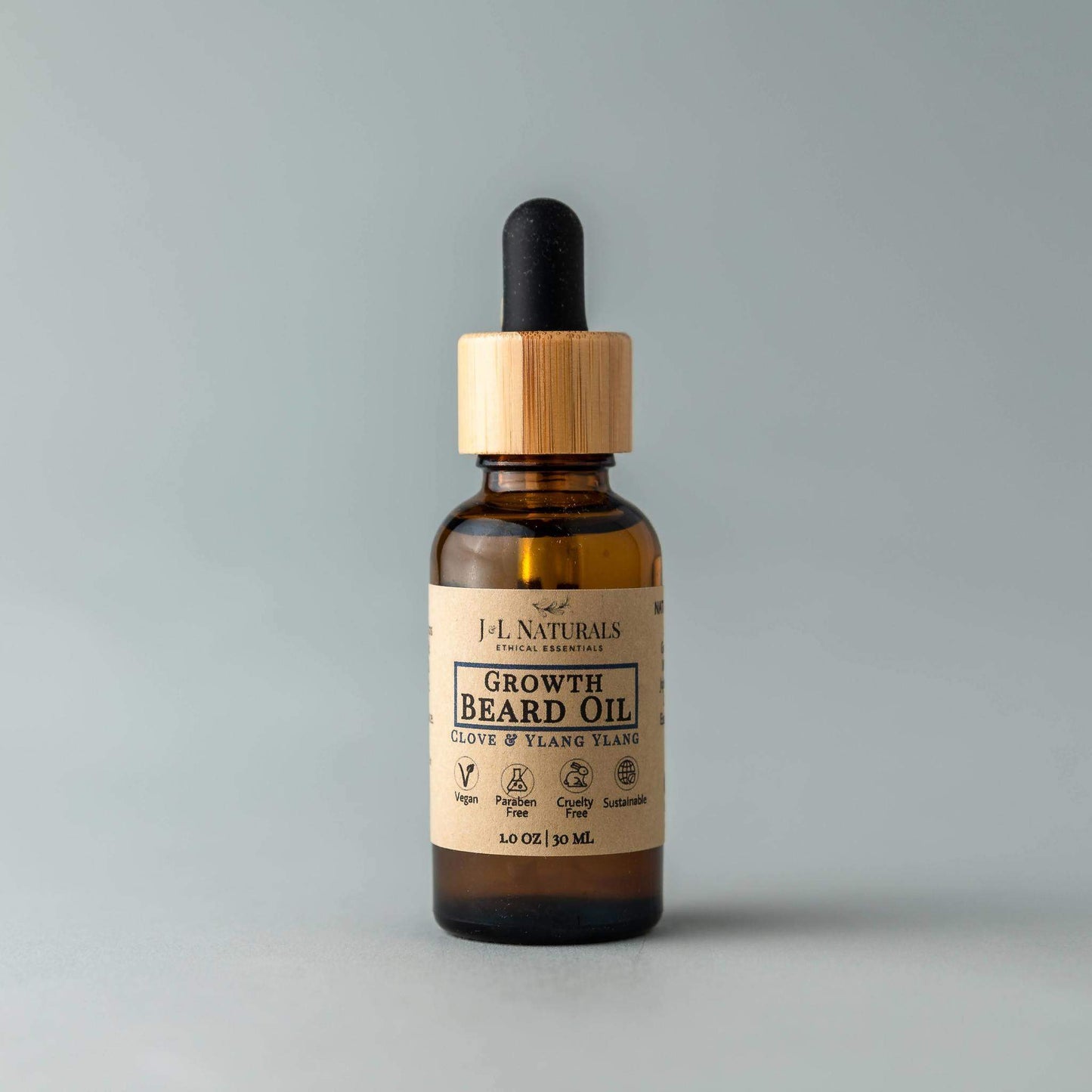 J&L Naturals Growth Beard Oil in Cedarwood & Tea Tree scent, displayed upright with bamboo dropper lid against a soft gray background.