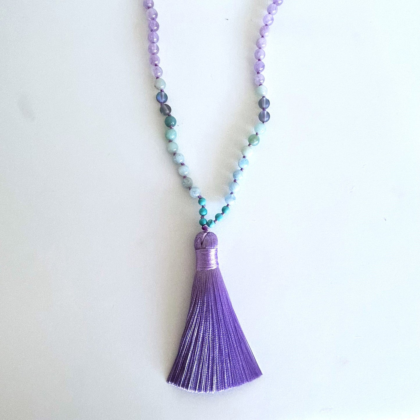 Mystic Mala crystal necklace laid flat to show bead arrangement and purple tassel
