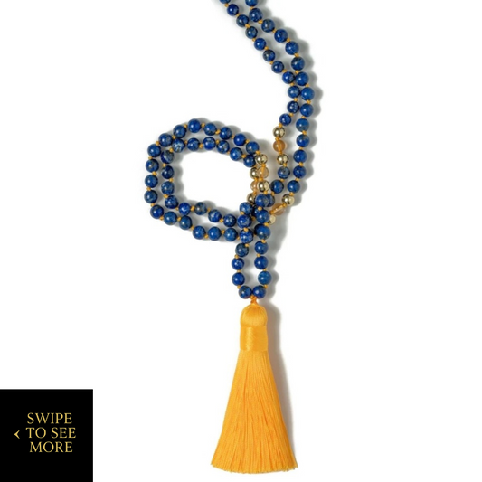 Lapis lazuli and citrine mala necklace with a golden tassel, coiled on a white background—hand-knotted beads for meditation, intention setting, and spiritual clarity.
